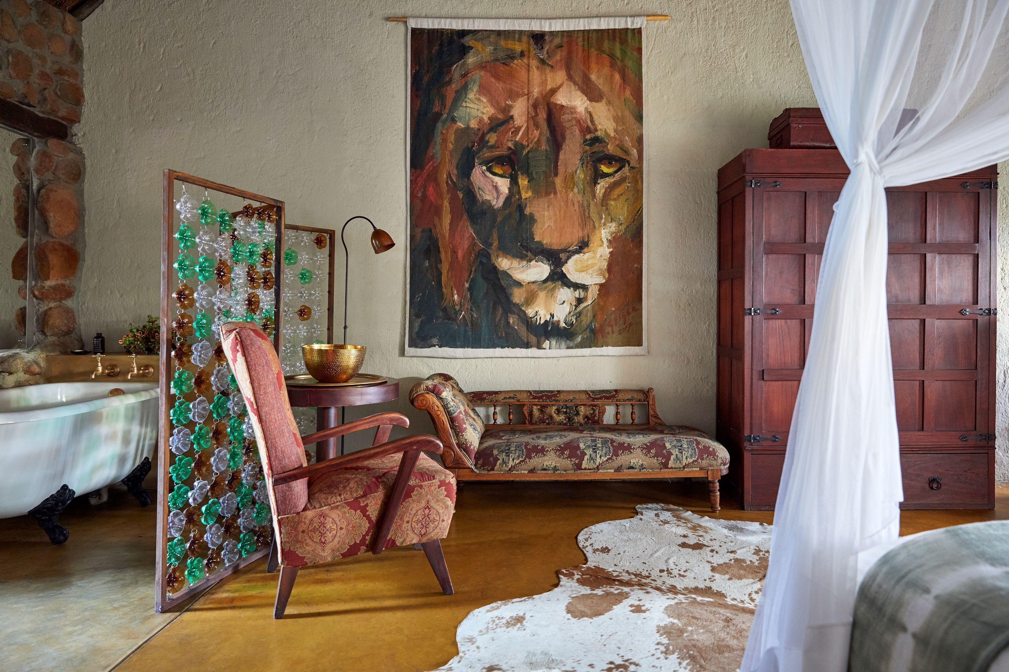 A room with a large lion painting, a wooden cabinet, a sofa, a chair, and a cowhide rug.
