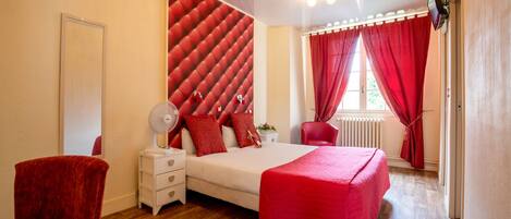 Un dormitorio con una cama, una mesita de noche, una silla y un cabecero rojo.