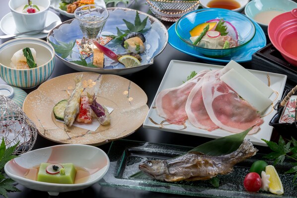 A variety of dishes including sushi, sashimi, and a whole fish on a table.