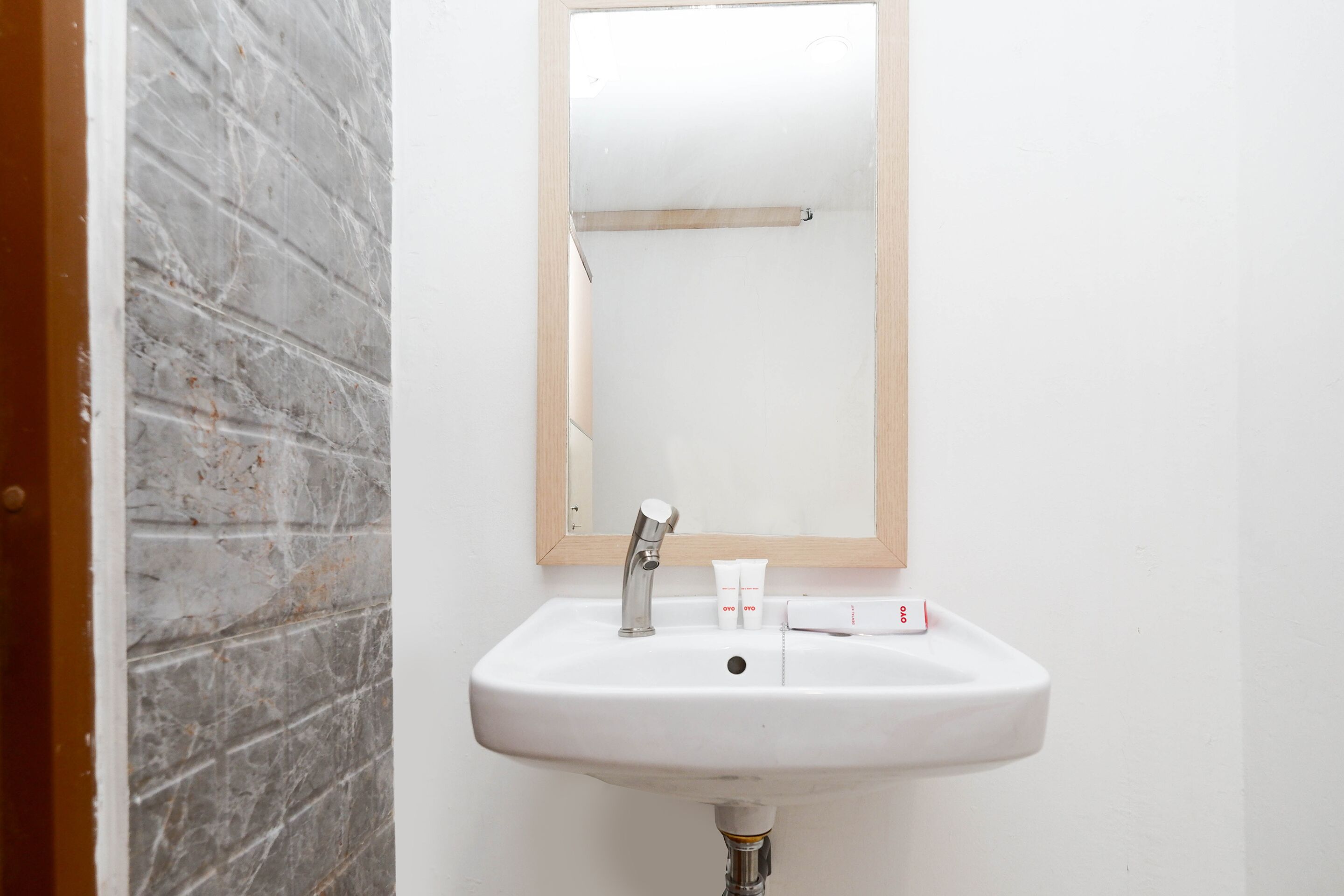 A bathroom with a white sink, a mirror, and a marble wall.