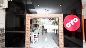 Una vetrina con un grande cartello rosso OYO, porte in vetro e un interno visibile con tavoli e sedie.
