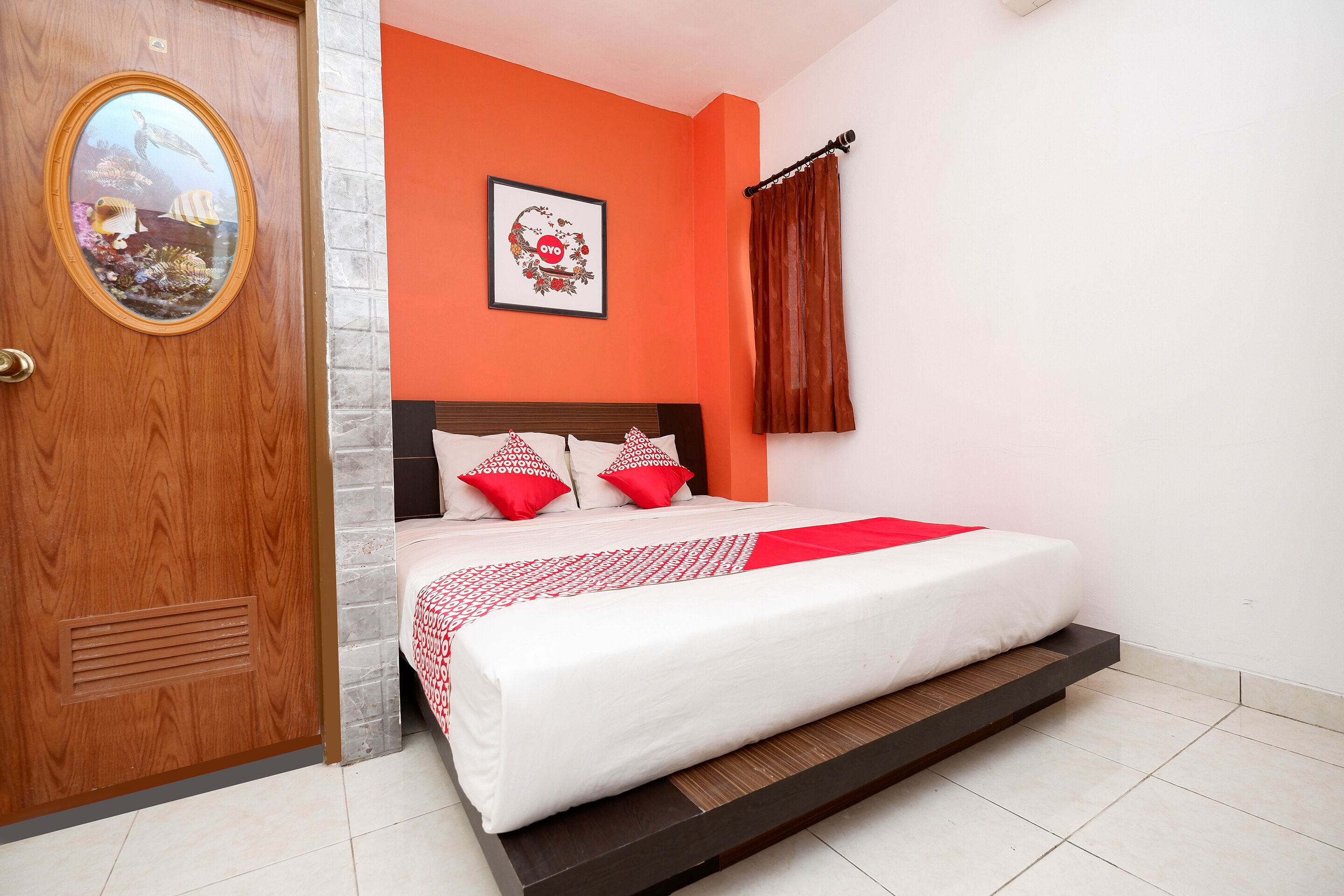 Un dormitorio con una cama, una puerta de madera, un espejo y un cuadro enmarcado en la pared.