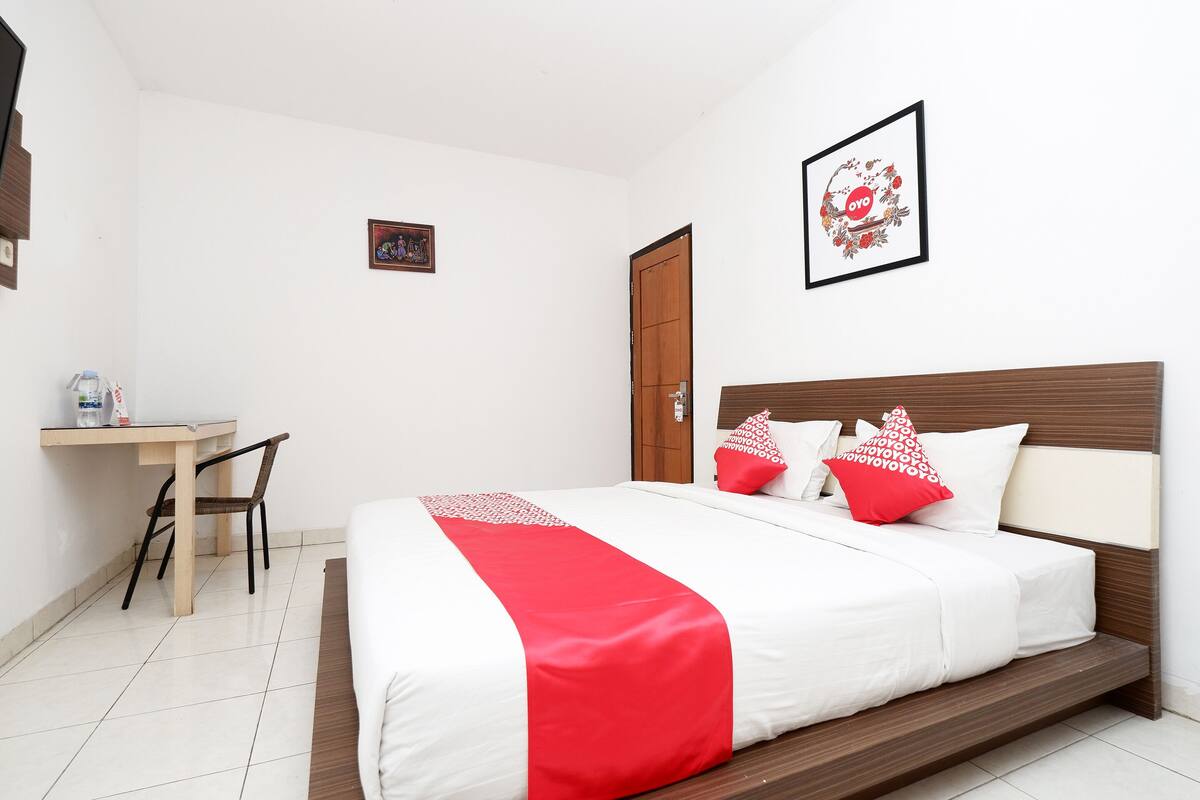 A neatly arranged hotel room with a bed, a desk, and a chair.