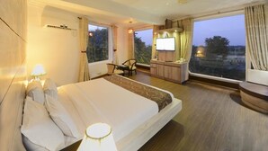 Una camera d'albergo con un letto grande, una scrivania con un computer, una sedia e una televisione.