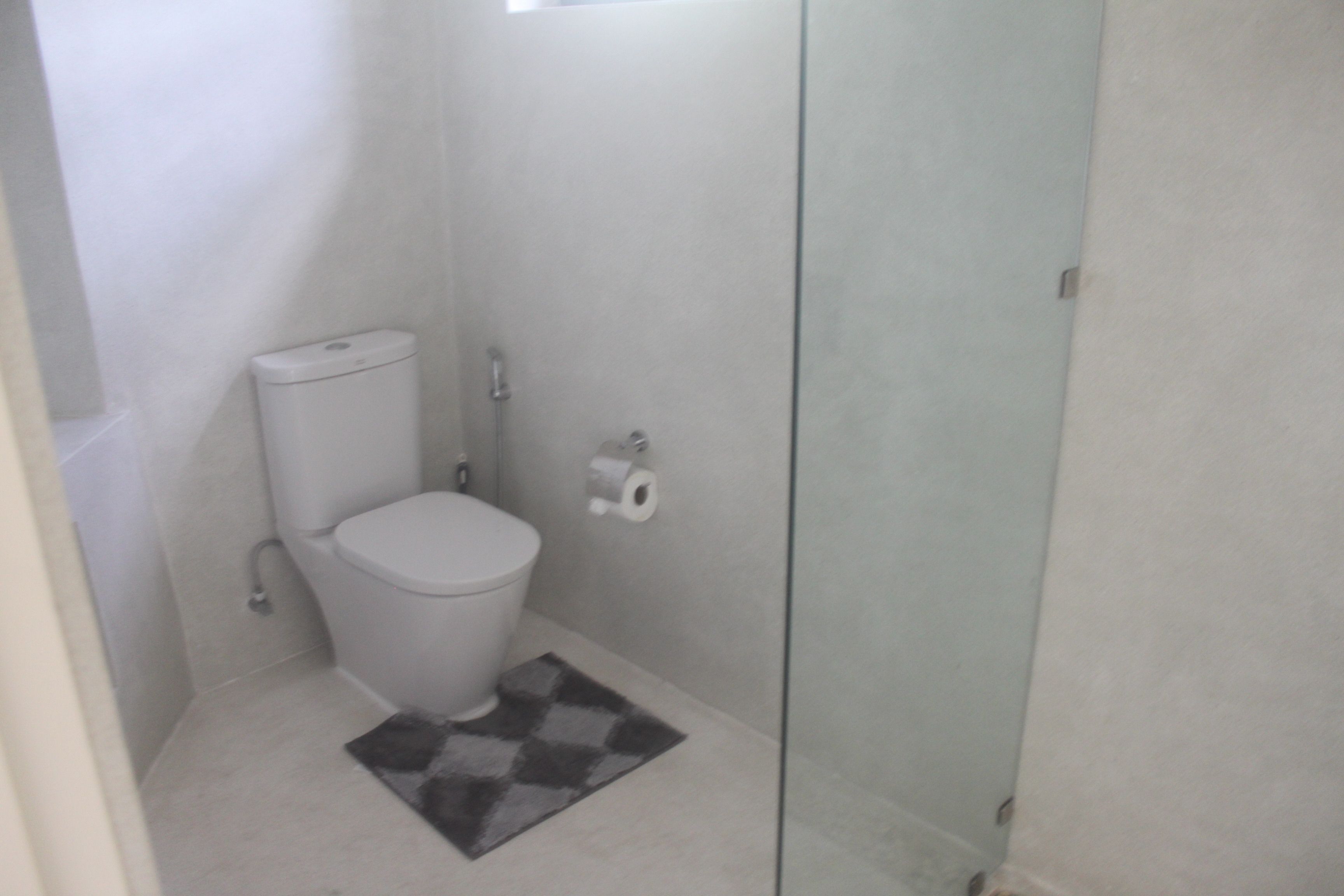 A small, modern bathroom with a toilet, a shower, and a glass shower enclosure.