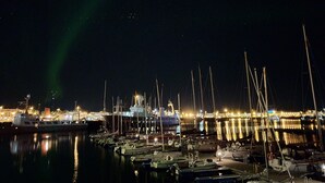 A marina at night with boats docked and a cityscape in the background. - Lækur Hostel (Reykjavik)