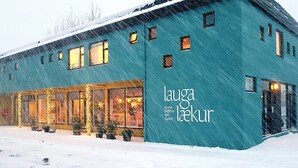A building with a sign reading "lauga laekur" and a storefront with lights and decorations. - Lækur Hostel (Reykjavik)