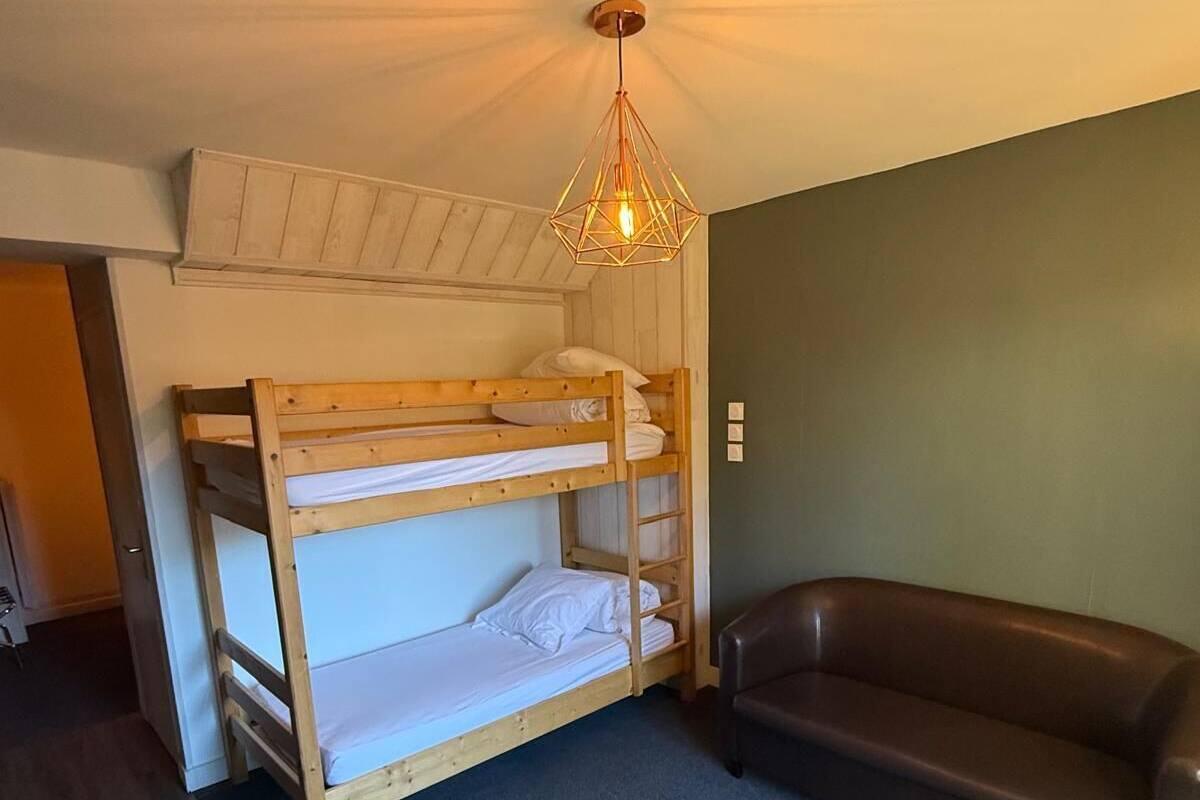 A bunk bed room with a brown leather couch and a table.