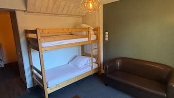 A bunk bed room with a brown leather couch and a table.