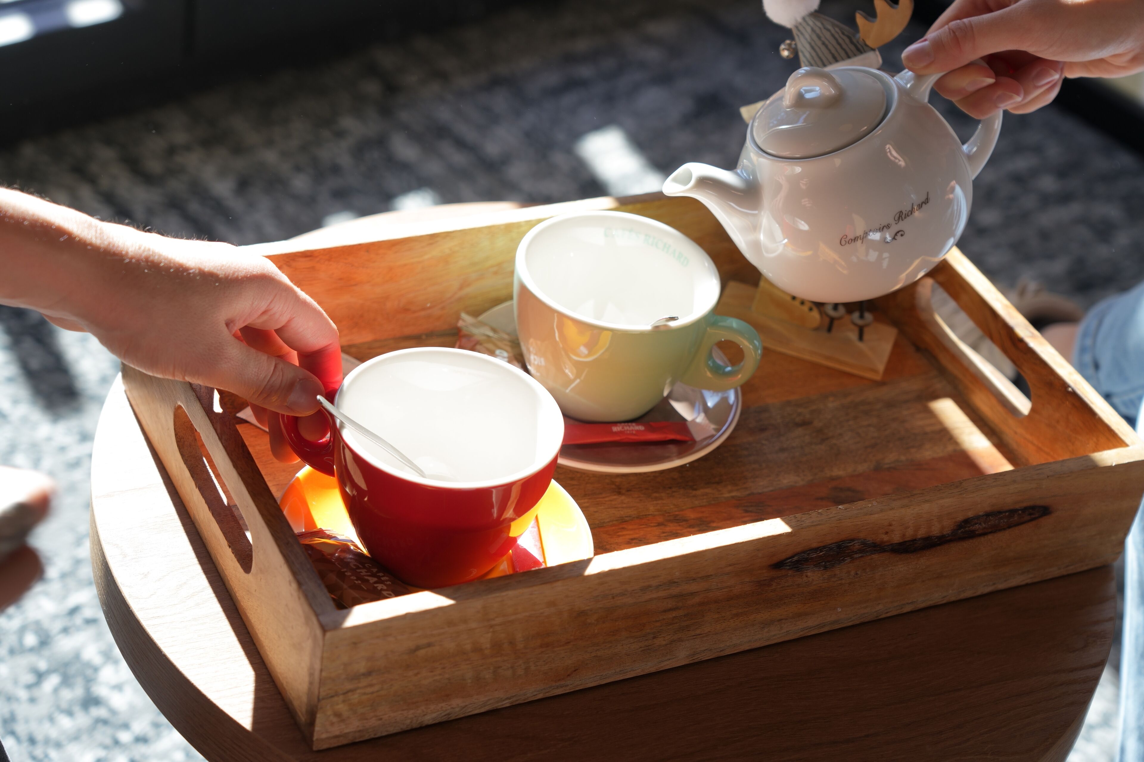 A tray with a teapot and two cups on a wooden surface.