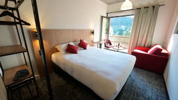 A hotel room with a large bed, a desk, a chair, and a view of the outdoors.