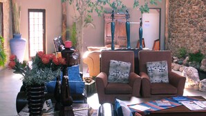 A cozy indoor setting with a thatched roof, stone walls, and comfortable seating. - African Tribes Guest Lodge & Conference (Kempton Park)