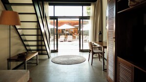 Un interior moderno con una escalera, una alfombra redonda y vistas a un área de estar exterior.