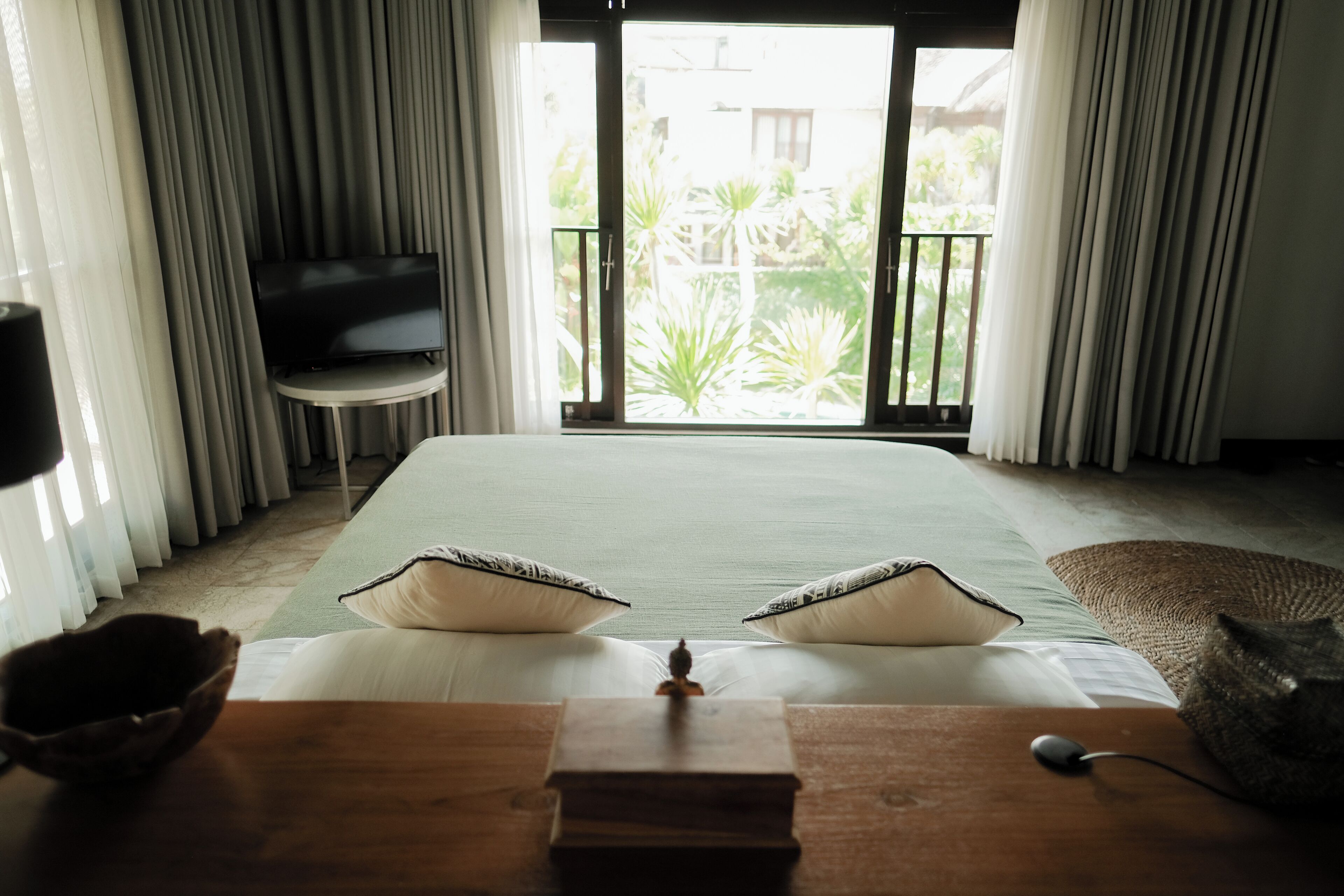 Habitación de hotel con cama, escritorio con computadora, televisión y vista al exterior.