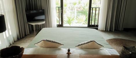 Habitación de hotel con cama, escritorio con computadora, televisión y vista al exterior.