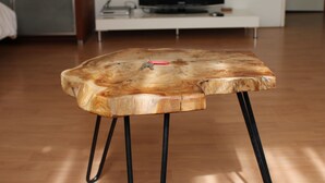 A wooden table with metal legs in a room with a TV on a white stand, wooden flooring, and a painting on the wall. - MyCityLofts - Schiekade (Rotterdam)