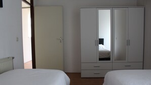 A bedroom with two beds, a wardrobe, and a door leading to another room. - MyCityLofts - Schiekade (Rotterdam)