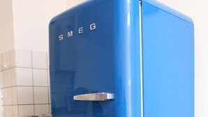 A blue refrigerator with the brand name "SMEG" on the top. - MyCityLofts - Schiekade (Rotterdam)
