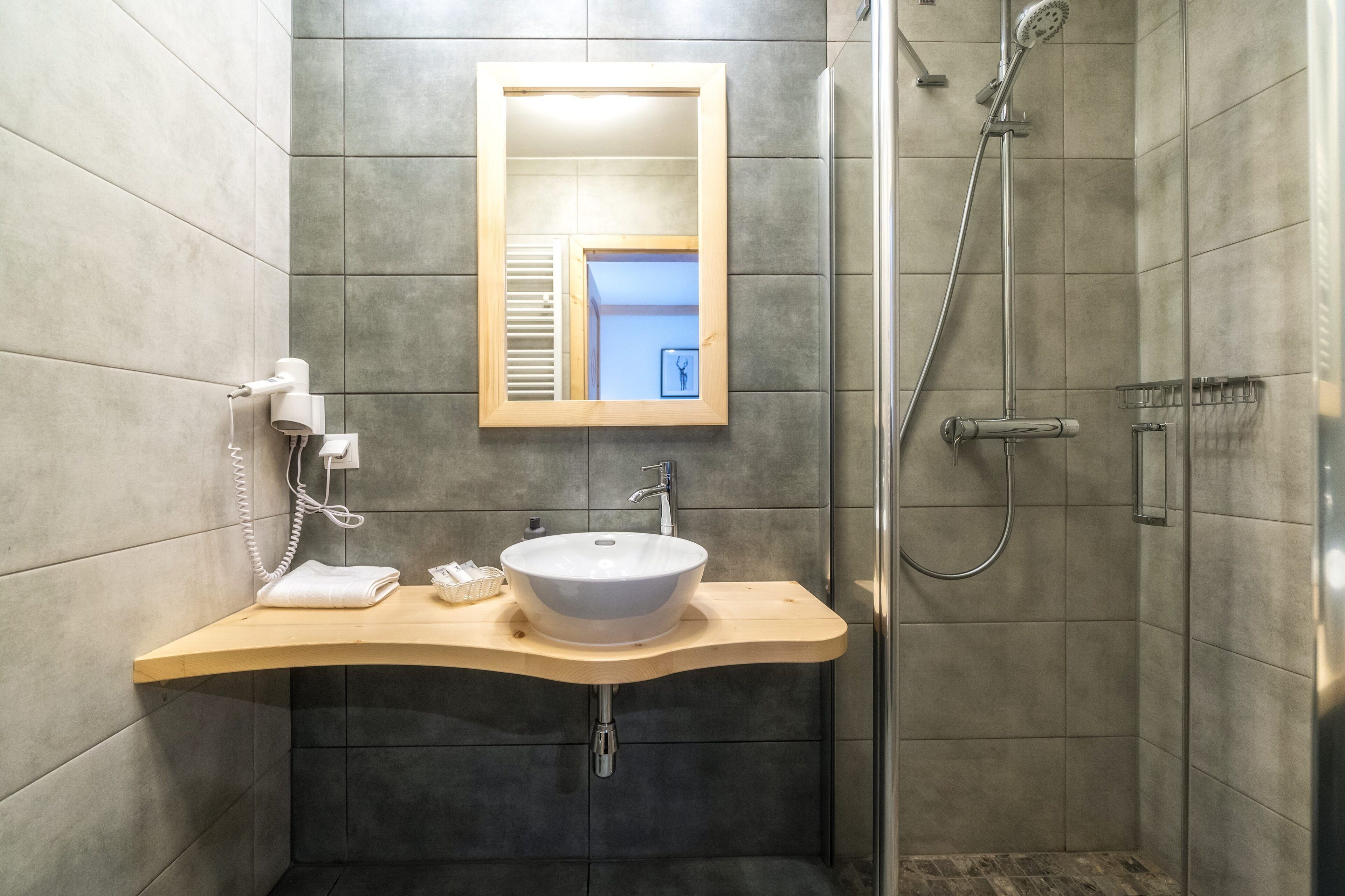 A modern bathroom with a curved sink, a mirror, a shower, and a toilet.