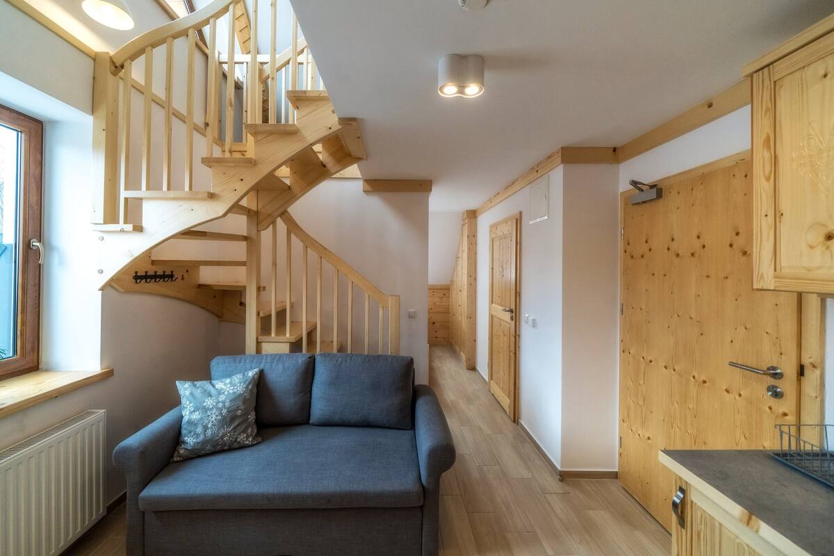 A modern interior with a wooden staircase, a sofa with a pillow, and wooden cabinets.