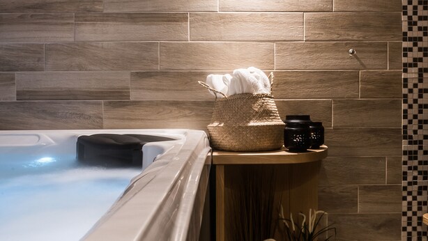 A bathroom with a wooden wall, a bathtub, a towel rack, and a small shelf with potted plants. - Kaplowa Chata (Zakopane)