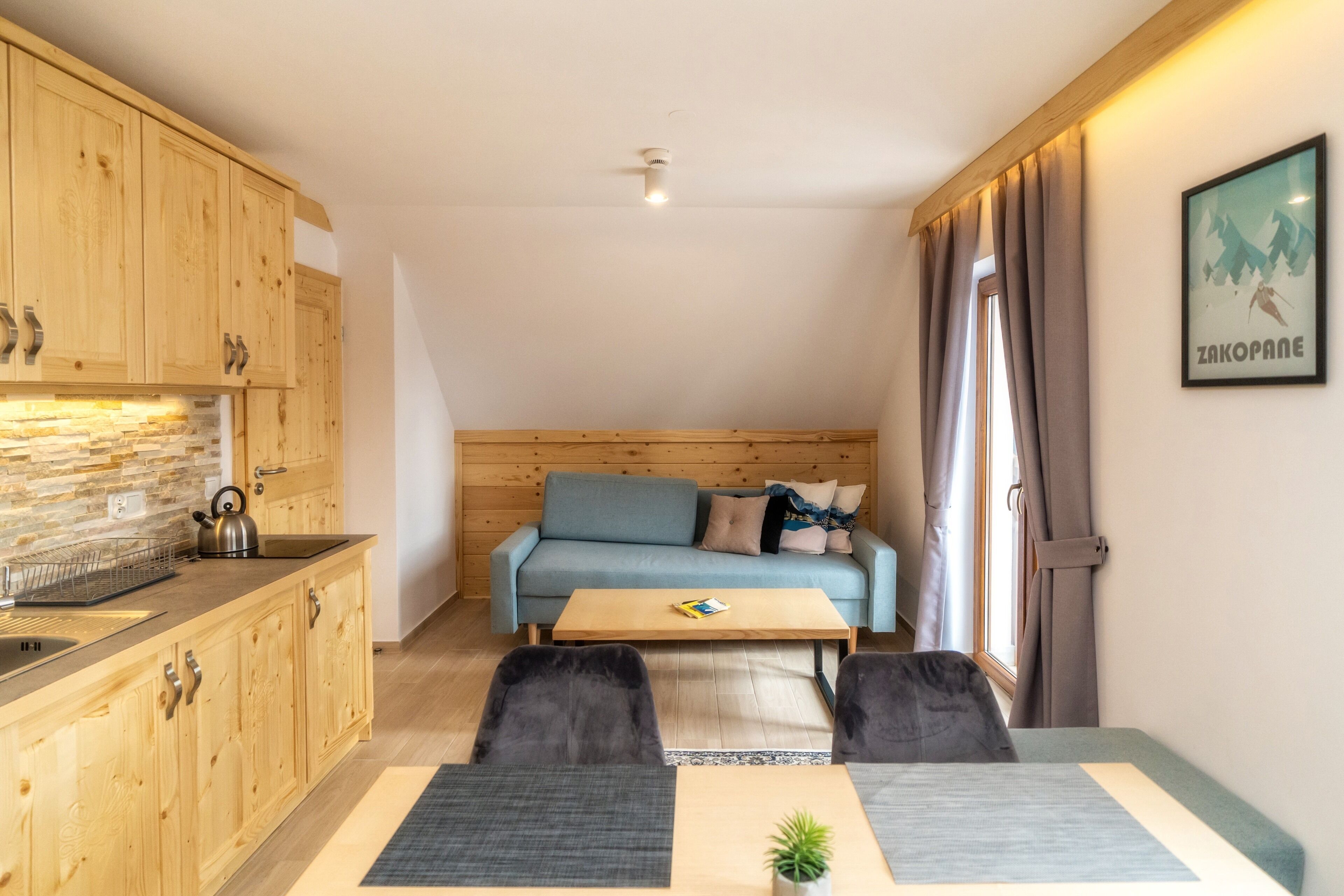 A compact living space with wooden cabinetry, a kitchenette, a sofa, and a small coffee table.