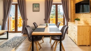 A dining area with a wooden table, black chairs, and a TV on the wall. - Kaplowa Chata (Zakopane)