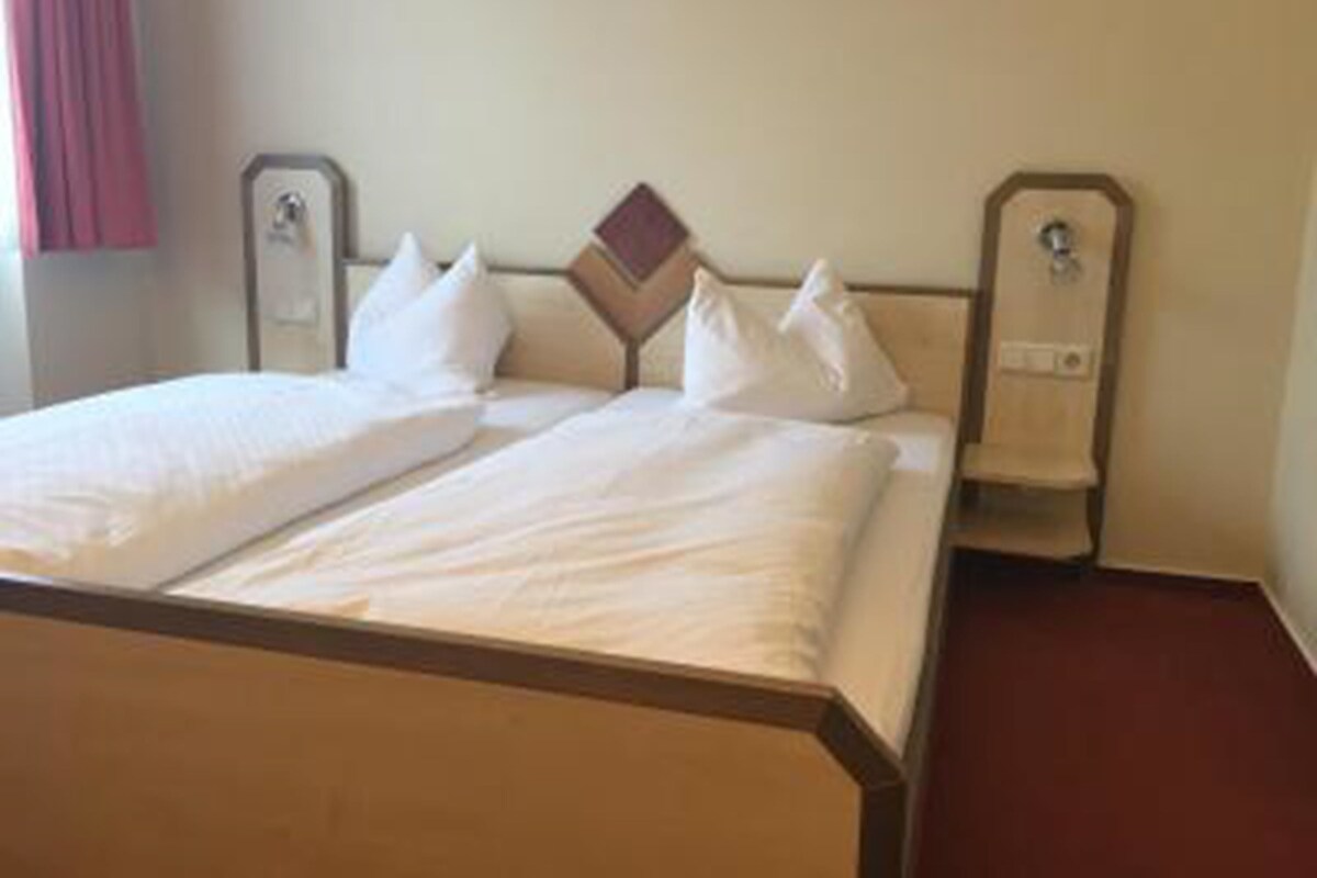 A hotel room with a bed, pillows, and a headboard.