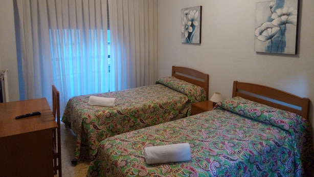 A room with two single beds, a wooden desk, a chair, and a window with curtains. - Pensión Cinco Villas (Logroño)
