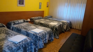 A hotel room with three beds, a wooden headboard, a large window with curtains, and a small painting on the wall. - Pensión Cinco Villas (Logroño)