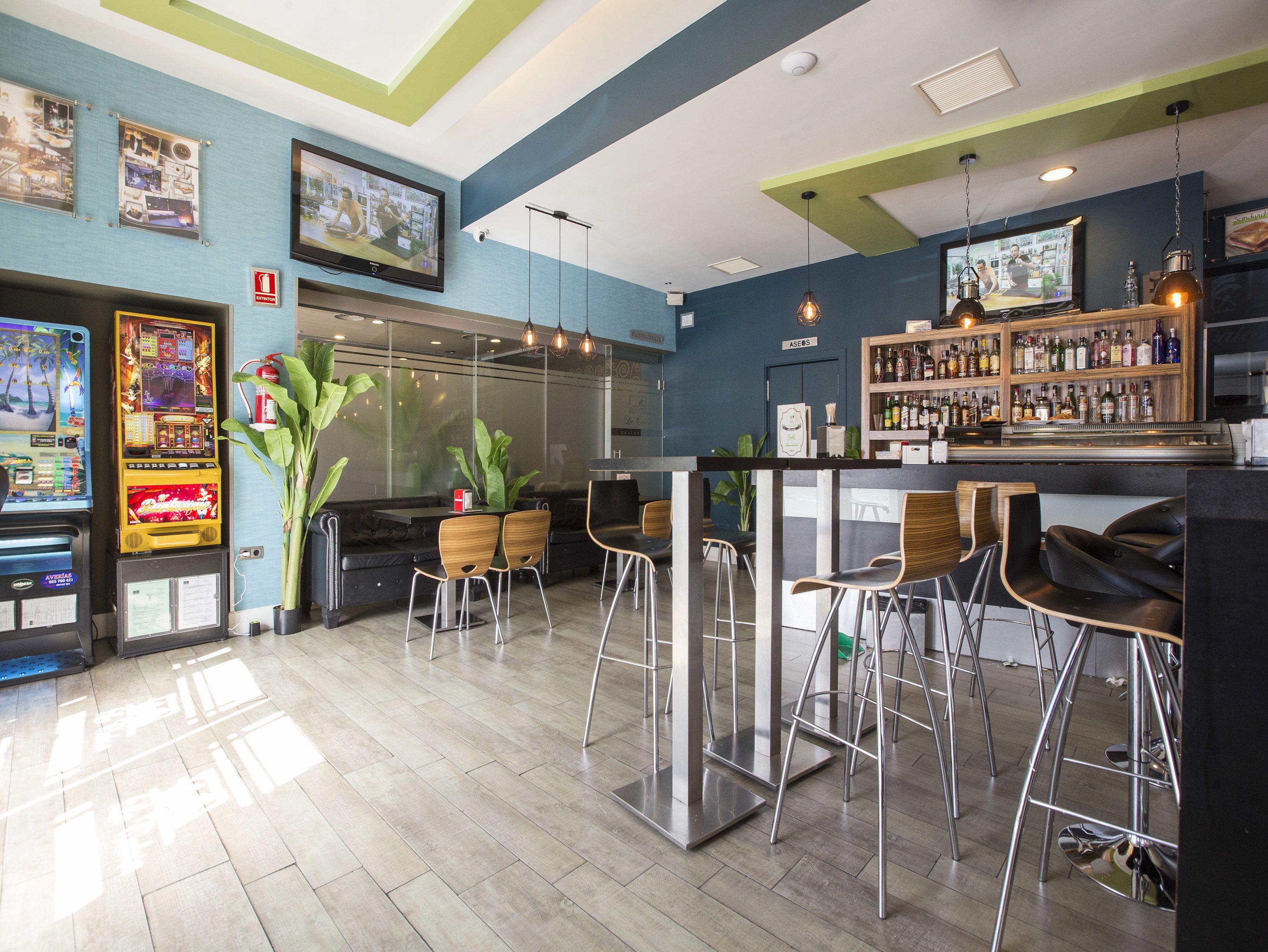 A bar area with arcade games, a bar counter, and stools.