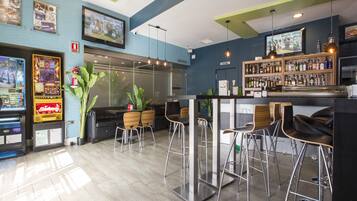 A bar area with arcade games, a bar counter, and stools.