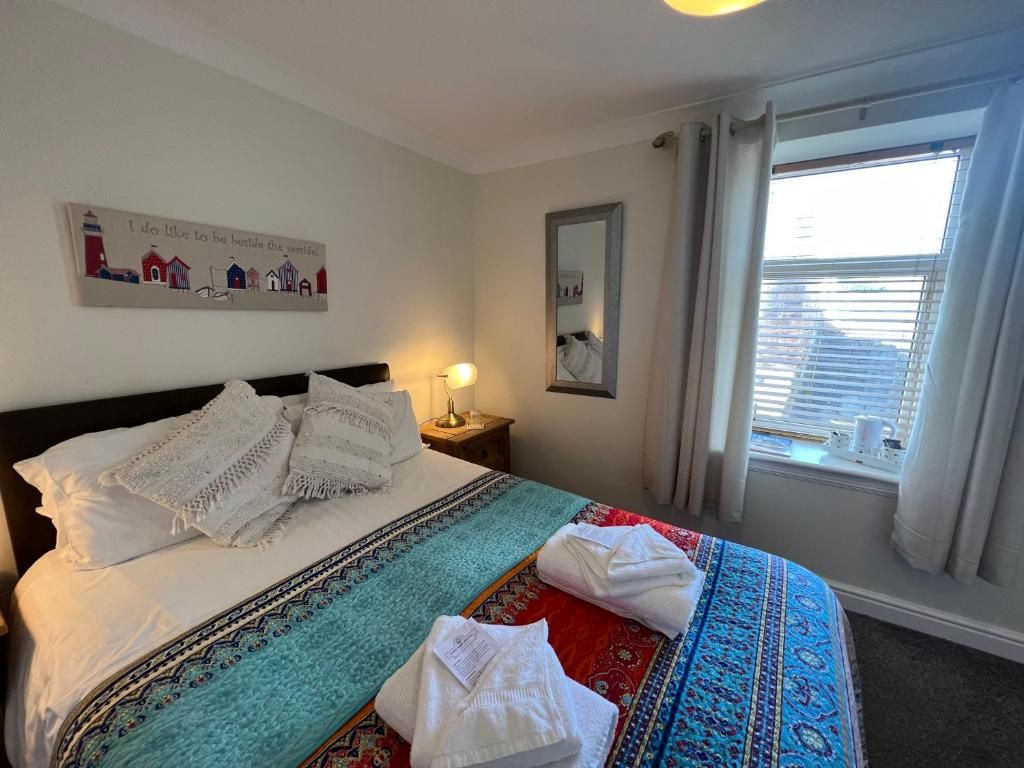 Una habitación de hotel con cama, mesita de noche, espejo y ventana con cortinas.