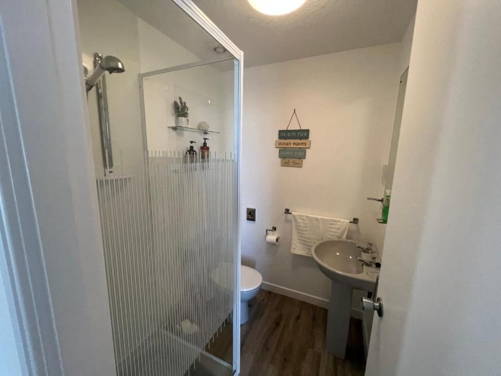 Et badeværelse med bruser, toilet, håndvask og et håndklædetørrestativ.