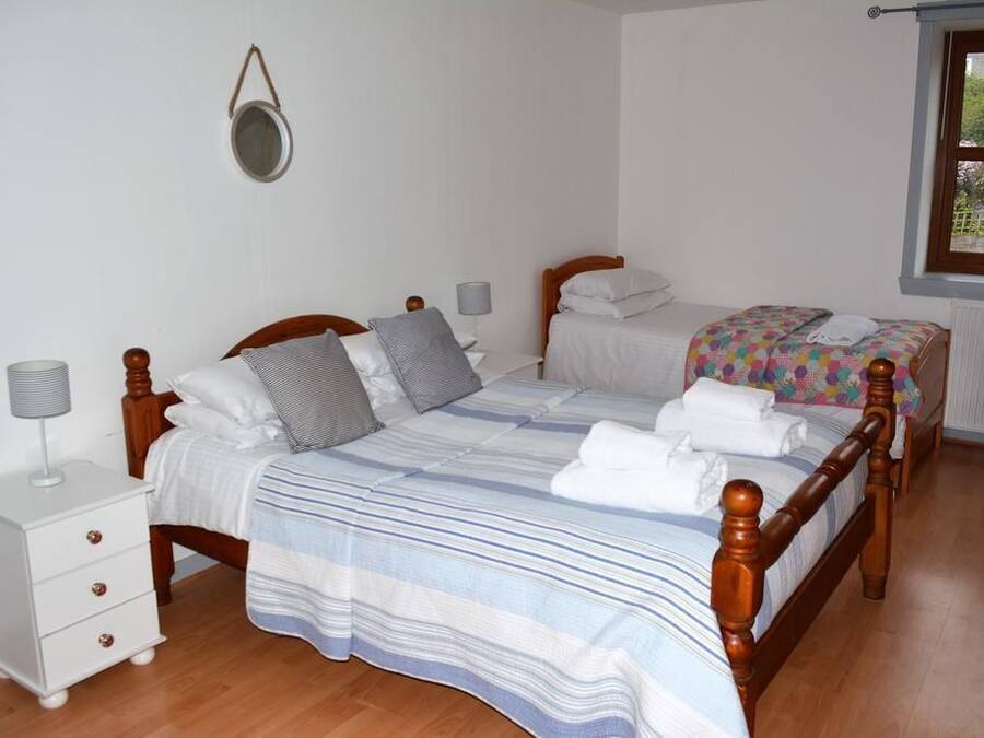 Un dormitorio con dos camas individuales, una mesita de noche con lámpara y una ventana con vistas a zonas verdes.