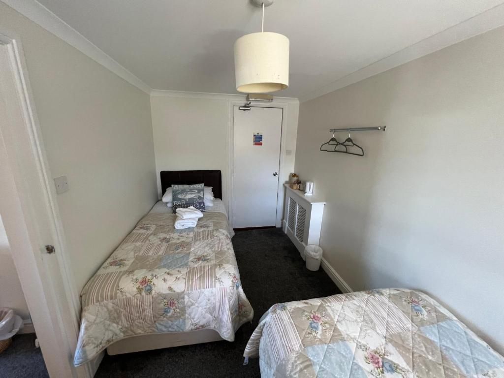 A small, clean room with two beds, a radiator, a coat rack, and a door with a sign.