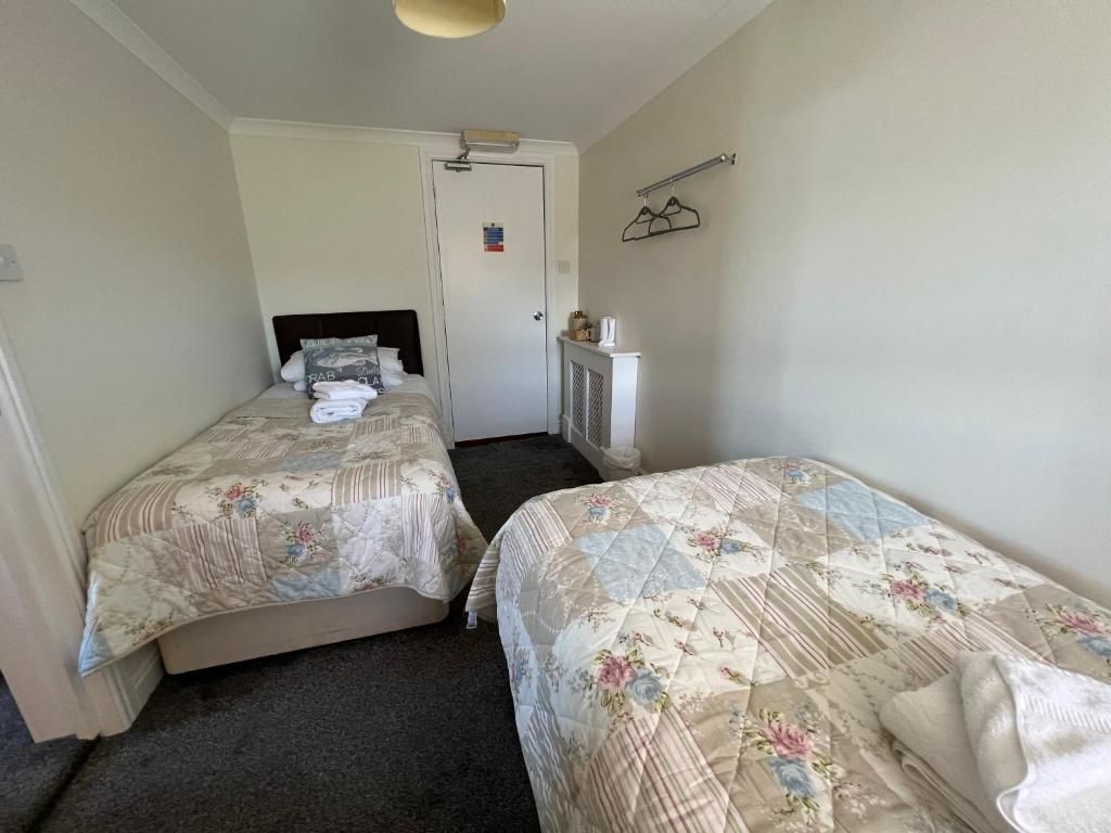 A room with two beds, a radiator, and a door with a sign.