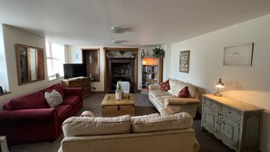 A living room with a fireplace, a television, a bookshelf, and a dining table. - The Anchor Hotel (Montrose)
