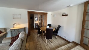 A cozy living room with a wooden floor, a dining table with chairs, a sofa, and a small desk with a lamp. - The Anchor Hotel (Montrose)