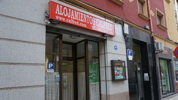 Un edificio con un letrero que dice 'Alojamientos Calfred' y un letrero de estacionamiento.