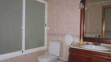 Un baño con inodoro, lavamanos y espejo.