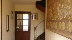 Ein Flur mit einer Holztür, einer Treppe mit Metallgeländer und einer großen Wandverkleidung.