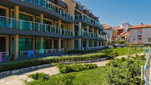 A multi-story hotel with balconies, a landscaped garden, and a clear blue sky. - Black Sea Paradise (Sozopol)