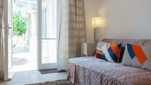 A bedroom with a bed, a nightstand, a lamp, and a view of the outside. - Apartments Cable car (Dubrovnik)