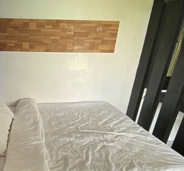 Una habitación con una cama, un panel de madera y una silla negra.
