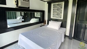 A hotel room with a bed, a large mirror, a window with a view, and a door. - Vinewoods Resorts by Cocotel (Taal)