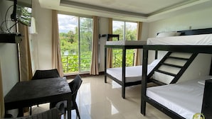 A room with bunk beds, a table, and chairs, large windows with a view of greenery. - Vinewoods Resorts by Cocotel (Taal)