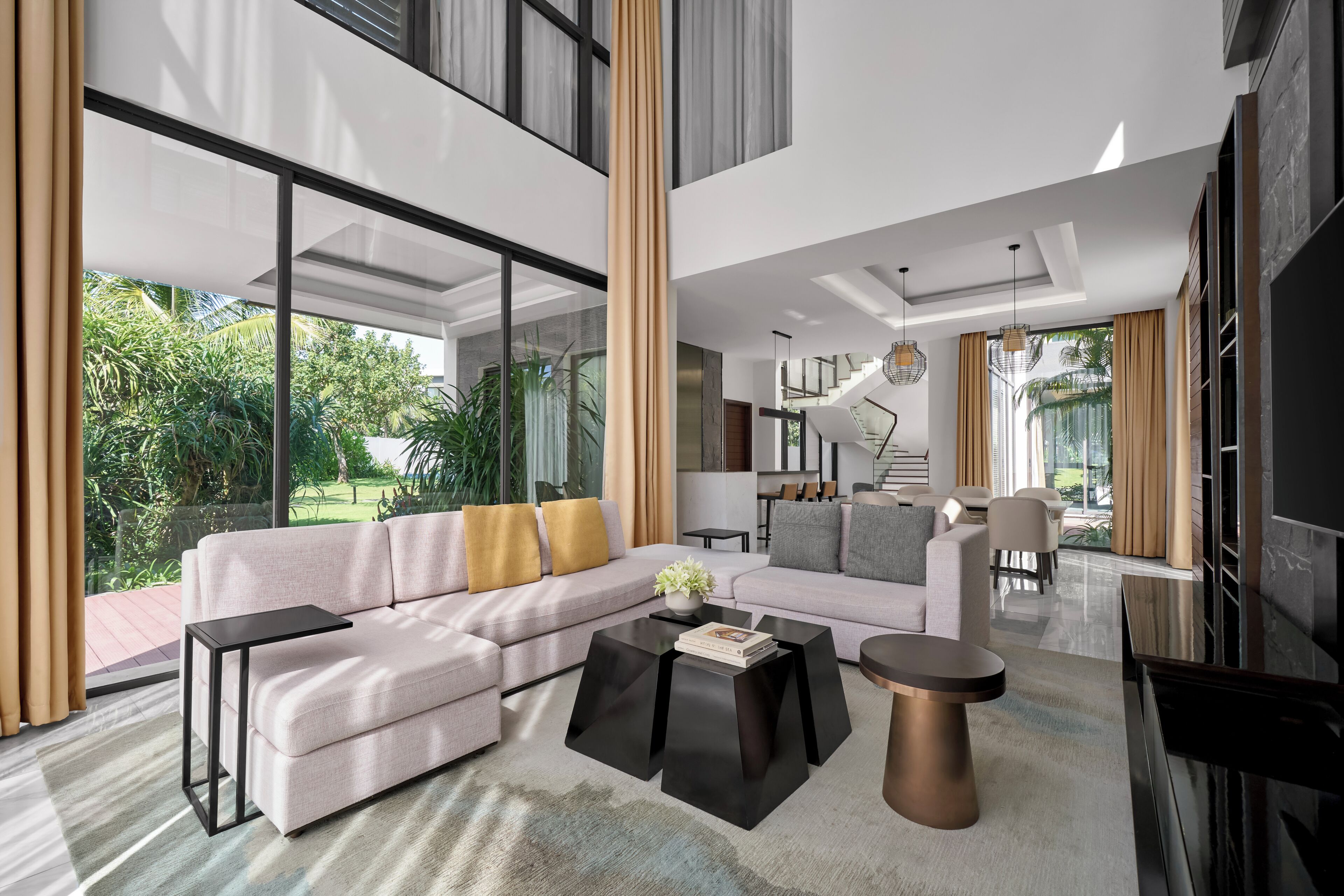 A modern living room with a sectional sofa, a coffee table, and a dining area with chairs.