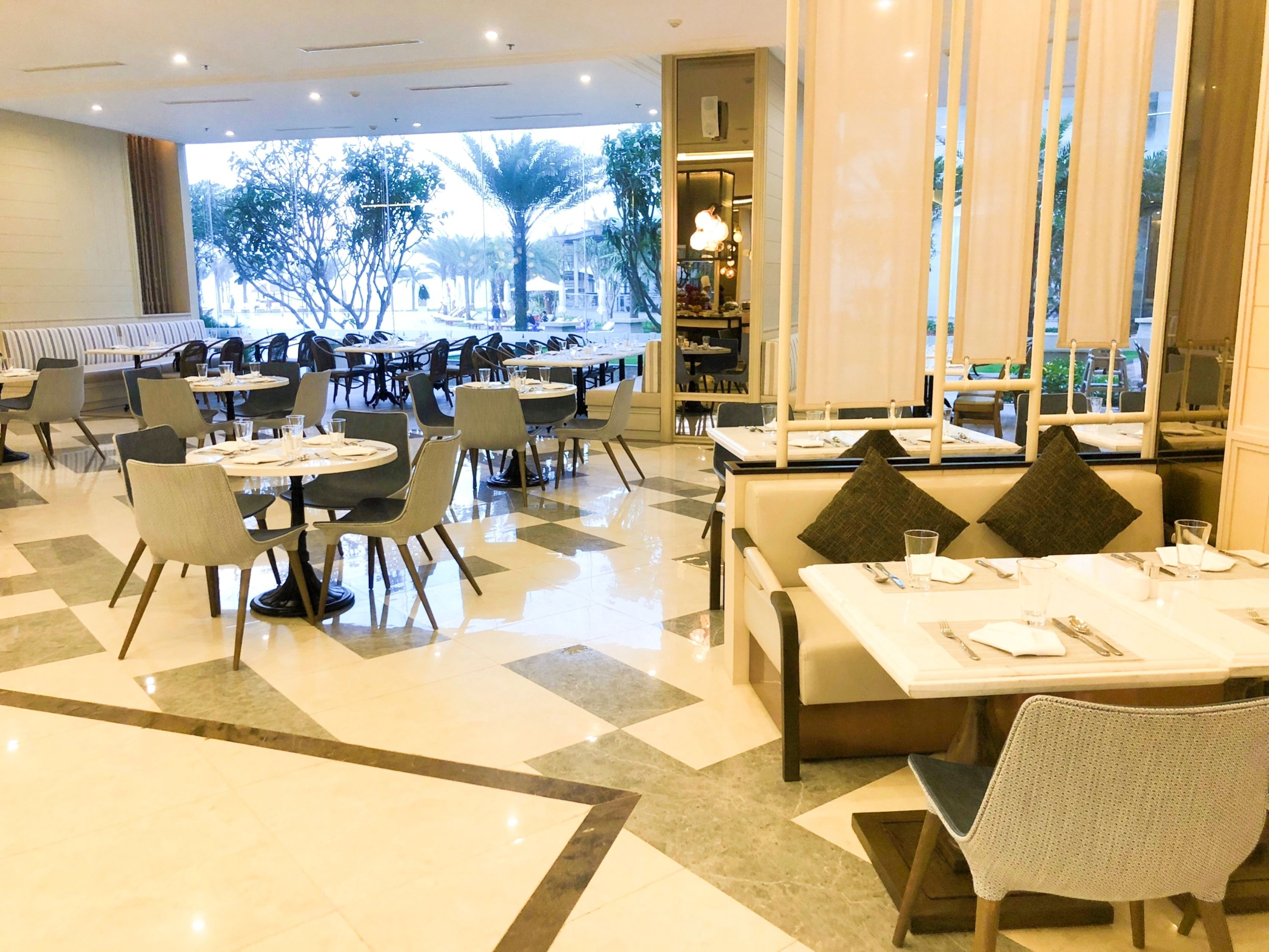 A spacious restaurant with multiple dining areas, including booths and tables, and a view of trees and buildings outside.
