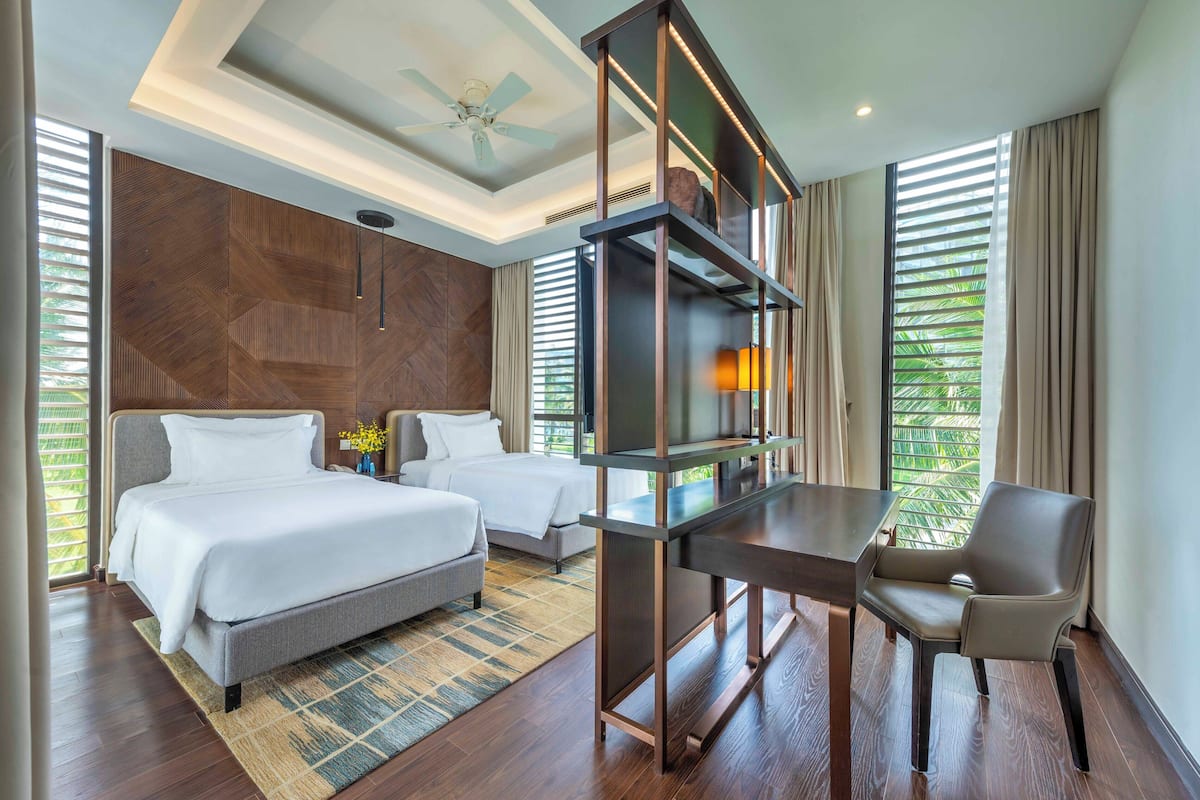 Une chambre d’hôtel avec un lit, un bureau, une chaise et un téléviseur.